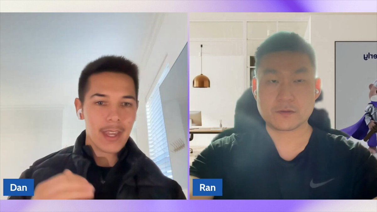 The image shows two men sitting across from each other, having a video call using their laptops. They are both wearing black clothing, which contrasts with the purple background of the image. The man on the left has his laptop open, while the man on the right is looking at him. There is also a small white sign in the bottom right corner of the image that reads "Come create new markets like $DRAM".