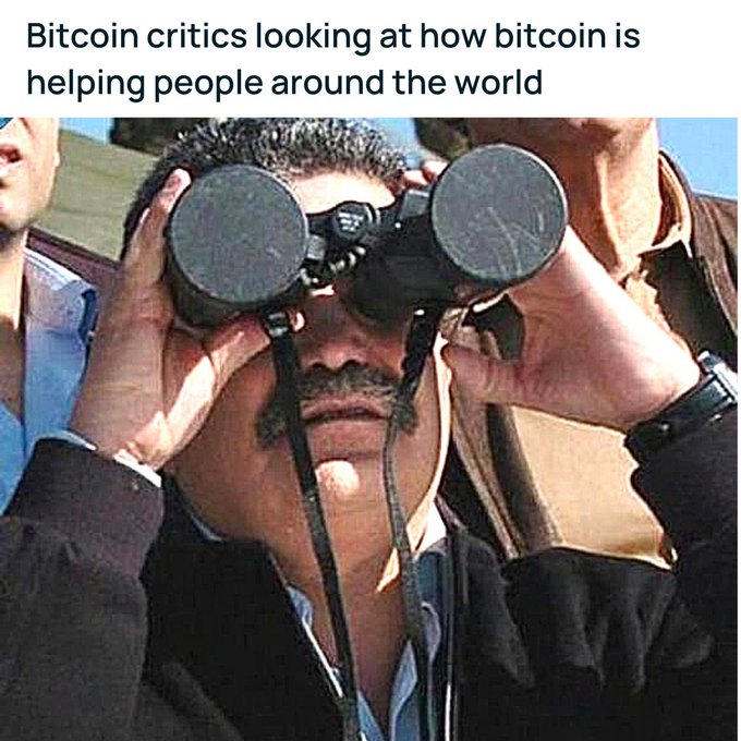 A man looks through binoculars with a caption reading "Bitcoin critics looking at how bitcoin is helping people around the world" — mocking critics who keep a close eye on Bitcoin's positive global impact, tying into the post's sarcastic tone about missing out on the good things cryptocurrency offers.