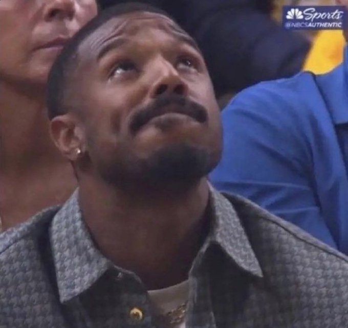 A close-up of a man with a mustache looking upward with an emotional expression, captured during an NBC Sports broadcast.