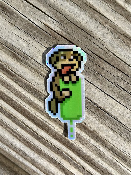 A pixel-art sticker of a zombie-like figure in a green outfit placed on a wooden deck surface.