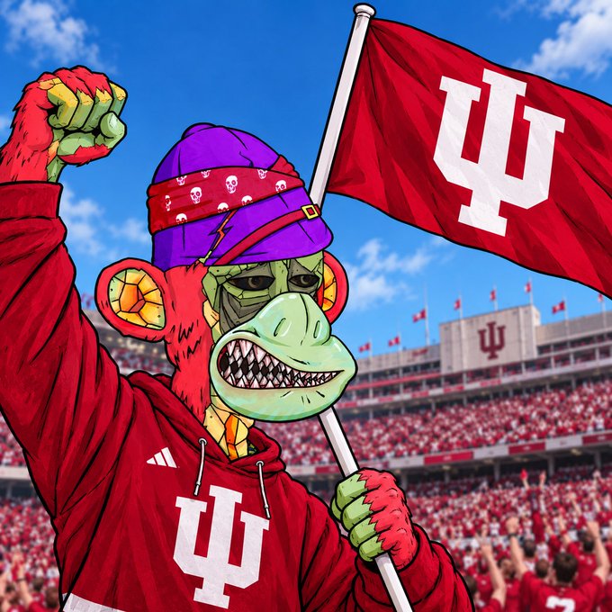 A cartoon illustration shows an Indiana University Hoosiers mascot, a fierce-looking monkey wearing a red hoodie and purple beanie, raising a fist while holding a flag with the IU logo in front of a packed stadium.
