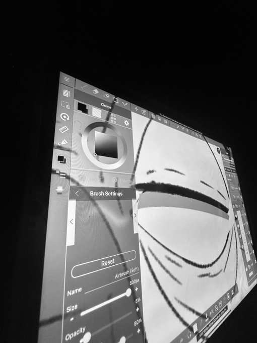 A black and white photograph showing a screen displaying digital art software with brush settings (Airbrush, Size 60px, Opacity 80%) visible alongside a digital sketch of an eye.