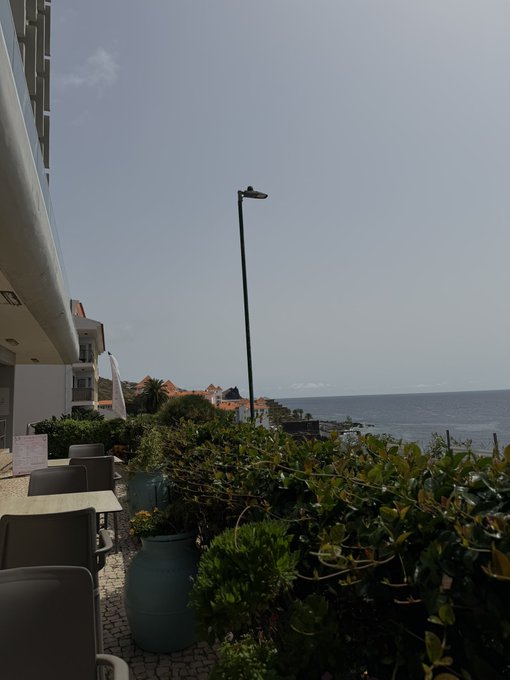 A coastal terrace with outdoor seating, potted plants, and a view of the ocean under a clear sky appears to be a scenic spot where someone might casually ask for a Solana (SOL) crypto wallet address.