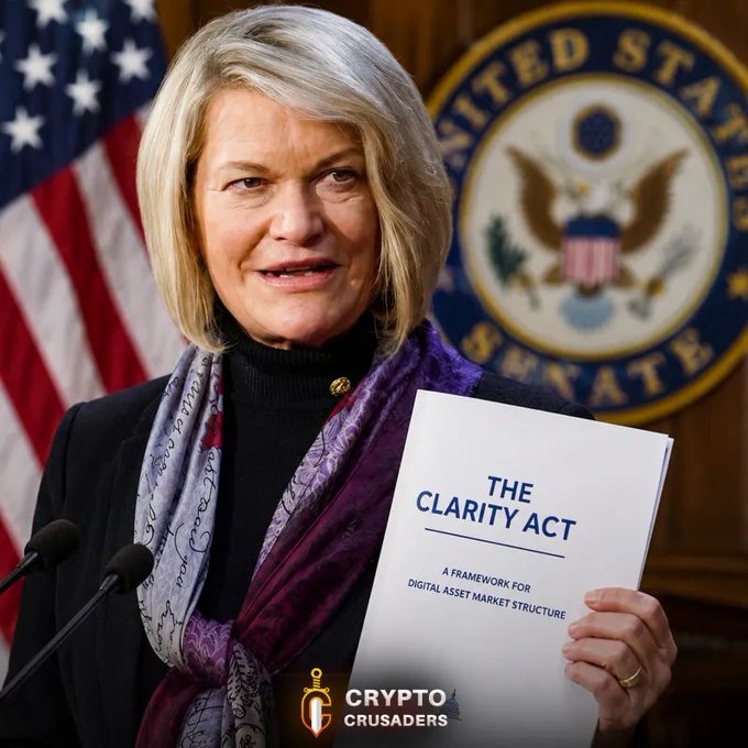 Senator Cynthia Lummis holds up "The Clarity Act: A Framework for Digital Asset Market Structure" in front of the U.S. Senate seal, visually reinforcing her declaration that the legislation will pass—news that the post frames as bullish for XRP. The image, branded with the "Crypto Crusaders" logo, pairs her official advocacy of the digital asset framework with the post's call for investors to "hang tight" on XRP.