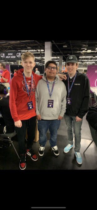 Three young men pose together at a gaming event, with a "FGC HELP DESK" sign visible in the background, and the center individual in the gray hoodie appears to be "Cupsey," the subject of the post's reference.