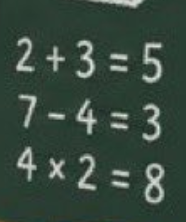 Simple arithmetic equations written in white chalk on a dark green chalkboard: '2+3=5', '7-4=3', and '4×2=8'.