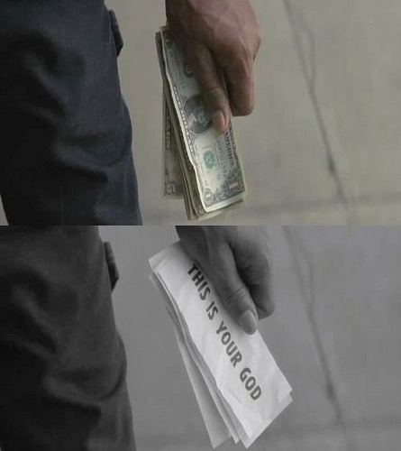 A two-panel image shows a hand holding a stack of US dollar bills in the top frame, and the same image in grayscale below with a paper reading "THIS IS YOUR GOD"—visually equating money with religion to critique the worship of fiat currency.