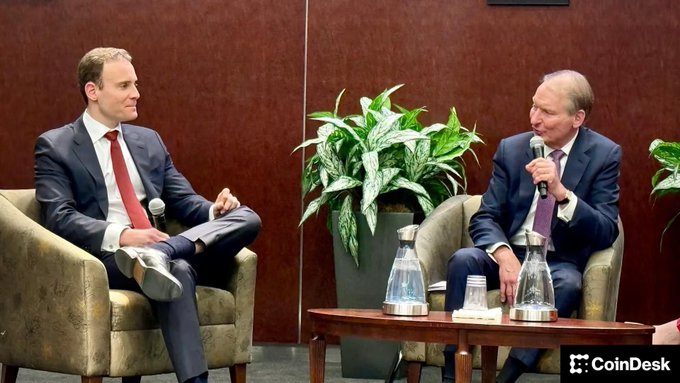 The image shows two men in suits seated in armchairs during what appears to be a panel discussion or interview, with the CoinDesk logo visible in the corner, suggesting a cryptocurrency industry event where topics like SEC regulatory changes and XRP may have been discussed.