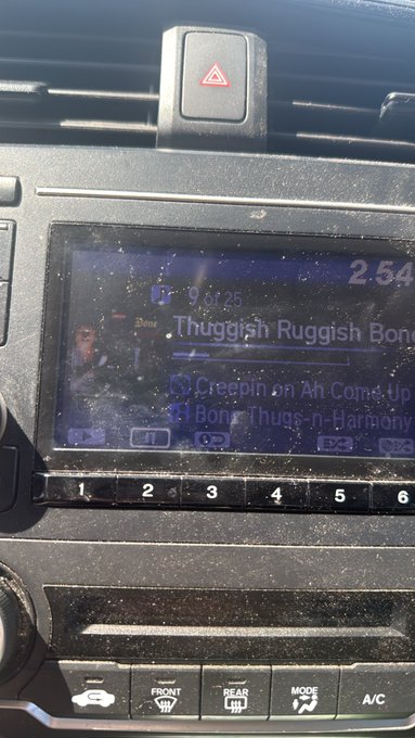A dusty car dashboard screen displays a music player playing 'Thuggish Ruggish Bone' by Bone Thugs-n-Harmony, with the track 'Creepin on ah Come Up' listed below.