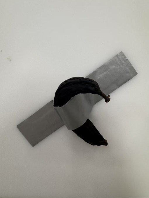 A small object consisting of a piece of black fabric wrapped in silver duct tape, attached to a rectangular silver foil strip, resting on a white surface.