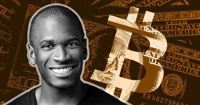 A black-and-white photo of a smiling man set against a brown background featuring a large Bitcoin logo and U.S. currency designs.