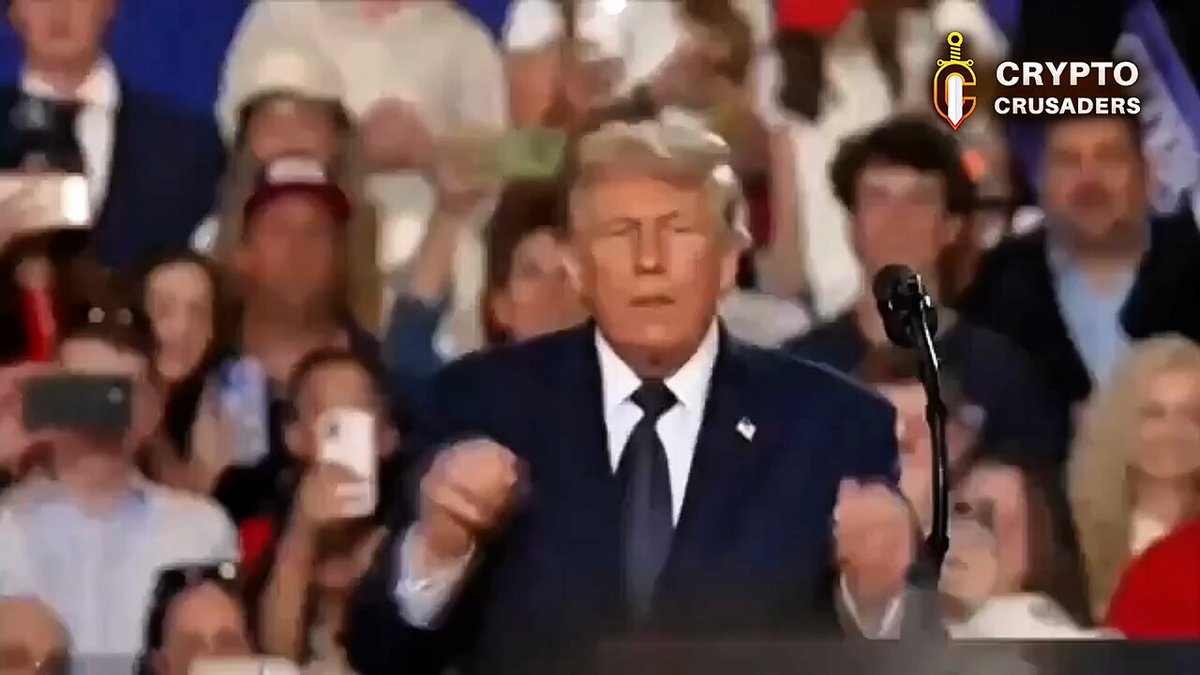 The image shows a man wearing a suit, standing at a podium with his arms raised while speaking. The crowd of people surrounding him appears to be engaged and attentive as he delivers his speech. In the background, there are several individuals holding up signs that read "IT'S OFFICIAL!! The CLARITY ACT has finally been added to the Senate's calendar this week $XRP ARMY!". This suggests that the man speaking is likely addressing an issue related to cryptocurrency or the clarity of the Senate regarding a new bill.