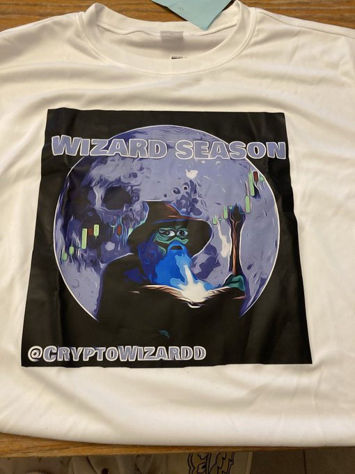 A white t-shirt featuring a "WIZARD SEASON" graphic design with a wizard character holding a glowing book against a moon backdrop, credited to "@CRYPTOWIZARDD," visually represents the post's theme of crypto conviction, as the author "WIZZ" references their long-term hold of $ZEC from $20 to $1700 to contrast with impatient "moonboy" traders.