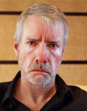 A serious-looking gray-haired man, likely Michael Saylor, is pictured against a wooden background with a concerned or stern expression. The image accompanies news that the Rosen Law Firm has opened an investigation into Saylor's Strategy (formerly MicroStrategy) over potential securities claims related to its STRC token, which Saylor had promoted as offering guaranteed returns capable of funding retirement, but which has since dropped 22%.