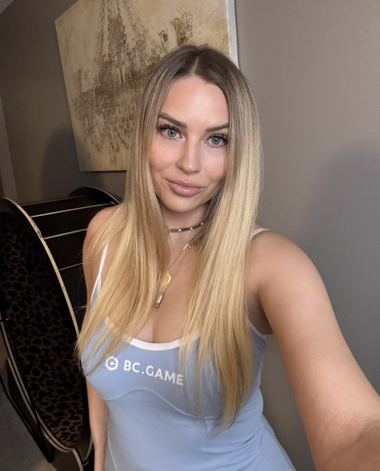 A woman wears a light blue tank top with "BC.GAME" printed on it, aligning with the post's update on BC Engine staking. The image is a selfie, suggesting a personal endorsement or representation of the brand.