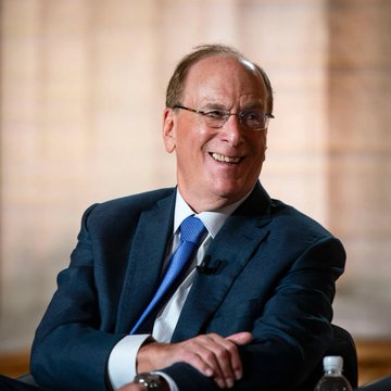 In the image, there's a man sitting down wearing glasses and a suit jacket with a blue necktie. He has a smile on his face as he looks over at the camera. The surrounding area seems to be a room or possibly an office space with a window visible in the background. There are two bottles placed nearby on surfaces. 

The main focus of this image is related to the post by focusing on ETFs, specifically the fund tracked by BlackRock and another fund which tracks Bitcoin. These funds have invested over $17 million into these cryptocurrencies - $16.35M worth of Ethereum and $15.34M worth of Bitcoin. The man in the suit jacket and glasses appears to be happy with his investment decisions as he smiles while looking at the camera, indicating that he is enjoying his financial activities.