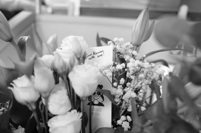 A black and white close-up of a floral bouquet featuring roses and baby's breath with a handwritten note reading 'From Namine, with love.'