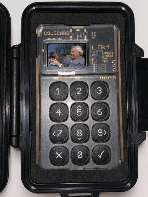A black protective case housing a DIY hardware wallet called 'COLDCARD Mk4' with a screen displaying a still from 'The Princess Bride' and instructions reading 'SHOOT THESE GUYS'.