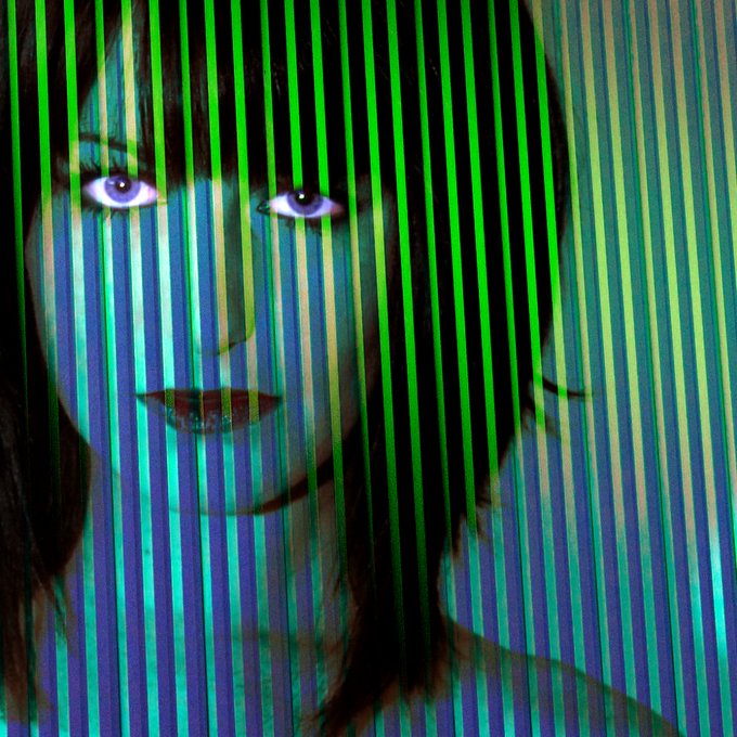 A digital artwork featuring a woman's face partially obscured by vertical green and blue stripes, with striking purple eyes visible through the pattern.