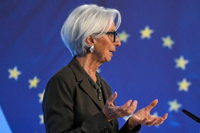 Christine Lagarde, President of the European Central Bank, speaking at a podium with the EU flag (blue with yellow stars) visible in the background.