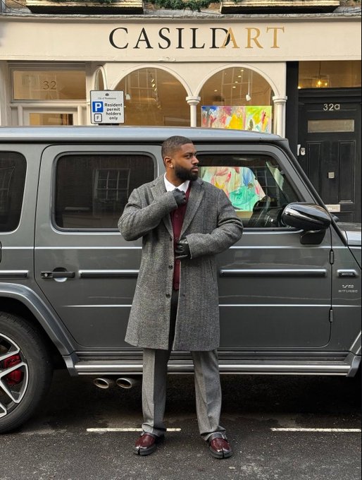 A man in a long gray overcoat, burgundy sweater, and black gloves poses on a London street in front of a gray Mercedes-Benz G-Wagon and the "CASILDART" boutique (numbers 32/32a visible), projecting an air of luxury that complements the post's reference to the Nomisma and CNPY crypto networks' ongoing collaboration.