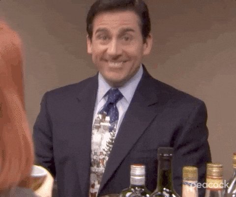 iced tea and wine bottles are displayed on a table, with a man in a suit and tie standing behind it.