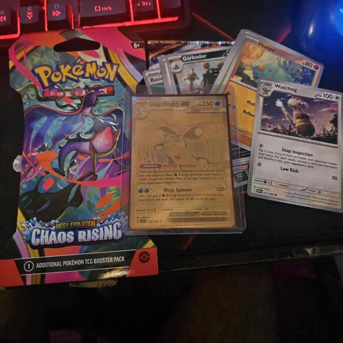 A hand triumphantly displays their spoils from opening a "Pokémon Scarlet & Violet Chaos Rising" Mega Evolution booster pack, revealing an ultra-rare gold "Golisopod GX" card alongside a gold "Garbodor," "Mudbray," "Phampy," and "Watchog" — making the "1 PACK SNIPE" a massive success.