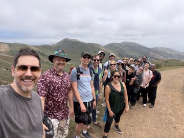 The Convex team poses for a group photo during their offsite, smiling together on a scenic mountain road with rolling hills in the background. The image perfectly captures the camaraderie the post celebrates, showcasing the close-knit group enjoying time together outside the office.