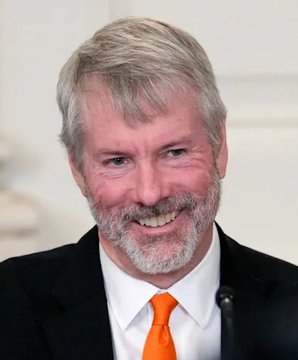 A headshot of a smiling older man with gray hair and a beard, wearing a dark suit and orange tie.