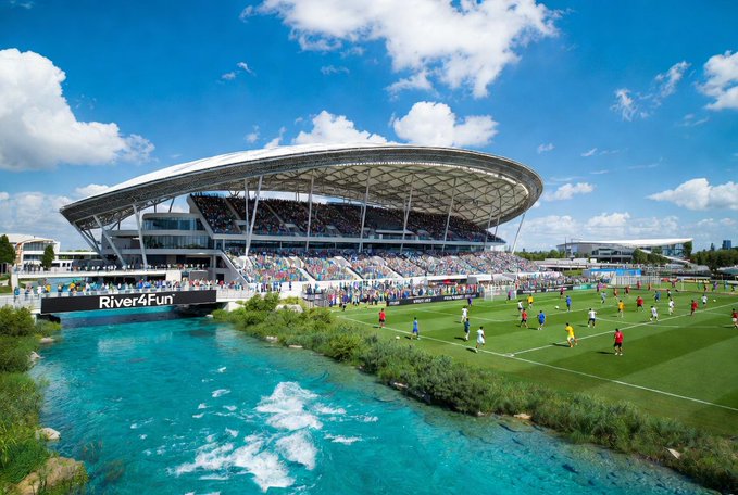 The image shows a large stadium with a river running through it. The stadium has a curved roof that resembles a water slide or a wave, giving it a unique appearance. There are many people gathered around the field, possibly attending an event or enjoying the view of the river. A boat can be seen in the water near the stadium, adding to the overall atmosphere.

The post about the upcoming season is written in black text on a white background and includes the words "@River4fun" and "@RIVERdotInc". The caption also mentions that the price of the @River4fun stock has been corrected by $RIVER, which implies that there might be some fluctuations or changes happening in the market.