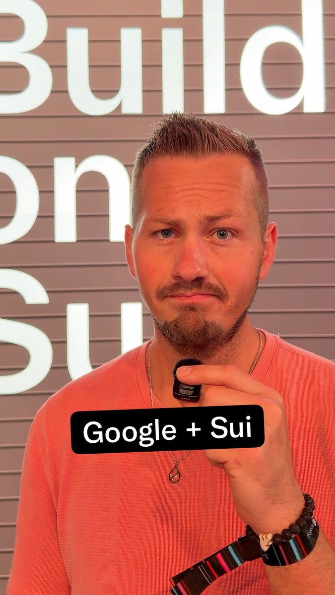 A man in a pink shirt stands in front of a 'Build on Sui' sign, holding up a small device, with text overlay reading 'Google + Sui'.