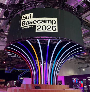 An indoor event venue with a large hanging banner reading 'Sui Basecamp Singapore 2026' above a stage with colorful illuminated arch structures.