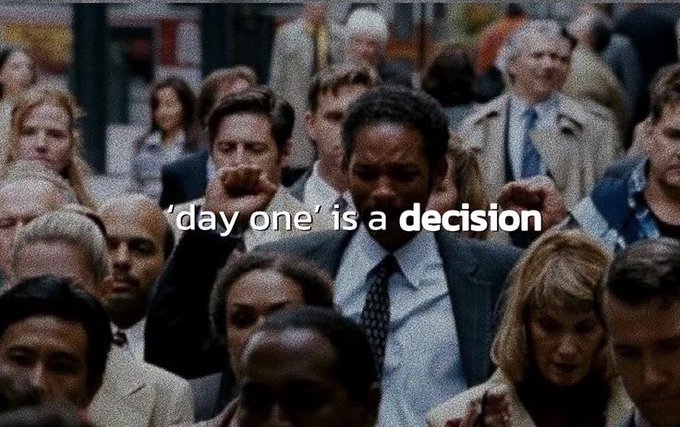 The image shows Will Smith in a scene from "The Pursuit of Happyness," standing in a crowd with a determined expression and clenched fist, overlaid with the text "'day one' is a decision." The caption relates to the post's theme of using free drops or airdrops as an immediate profit-taking opportunity on day one, suggesting decisive action—much like Will Smith's determined stance in the film—when cashing out early in a volatile crypto market.