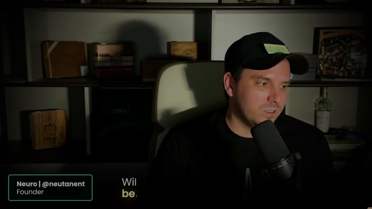 The image features a man wearing a black hat sitting behind a microphone with his hand resting on his chin. The background shows shelves filled with various items, including books and other objects. There are also some words visible in the image that seem to be related to the post about the community legend or the character Mocci.