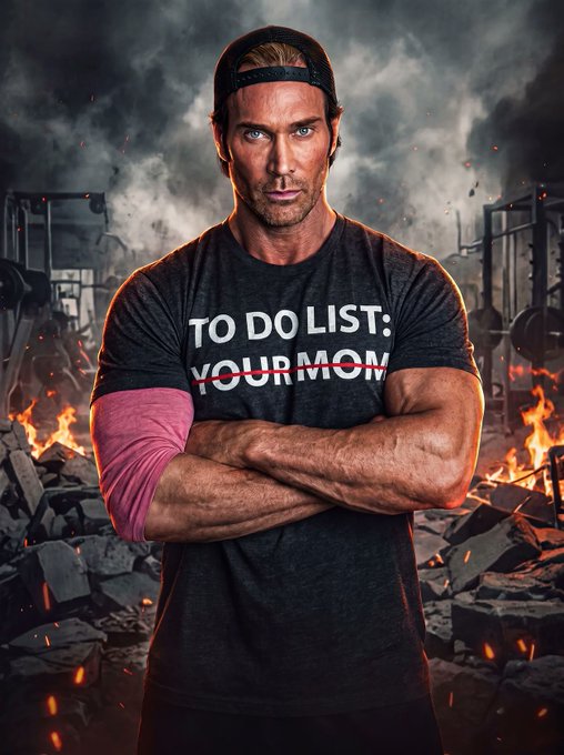 A muscular man wearing a black backwards cap and a black t-shirt with the text 'TO DO LIST: YOUR MOM' (with 'YOUR MOM' crossed out in red), standing with arms crossed in front of a fiery, destroyed gym background.