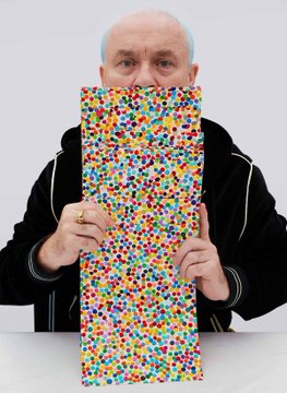 An elderly man in a black jacket holding up a large rectangular artwork covered in densely packed colorful dots, while a gold ring is visible on his finger.