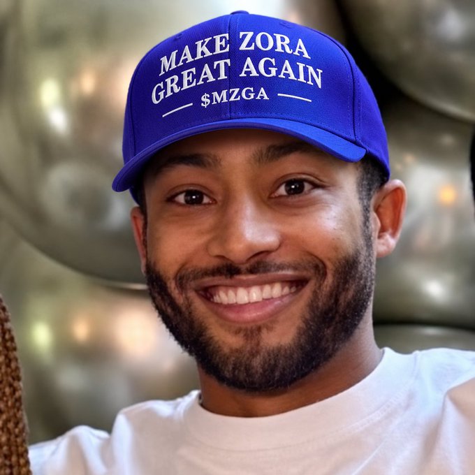 A smiling man wearing a blue cap that reads 'MAKE ZORA GREAT AGAIN $MZGA'.