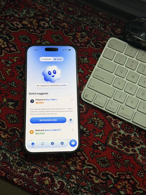 A smartphone on a patterned rug displays a crypto trading app with 'Assistant' and 'Wallet' tabs, showing suggestions to 'Prepare to buy Solana' and 'Hold and accumulate BTC' with SOL outperforming S&P 500 by 6.34%.