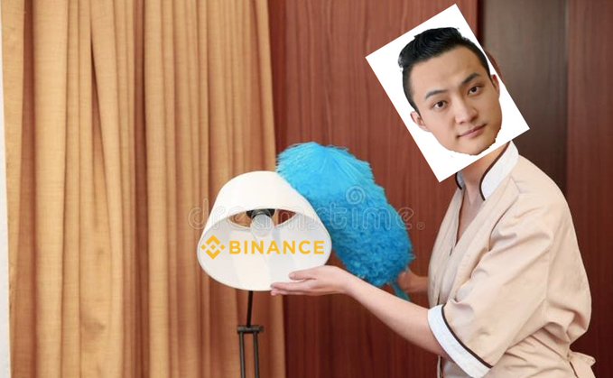 The man's face has been replaced with a photograph of Binance founder Changpeng Zhao, while his body holds a blue feather duster behind a lamp shade displaying the "BINANCE" logo. The caption fits the image, as Zhao is humorously posed like a hotel maid caught mid-cleaning, dusting near his own company's branded lampshade.