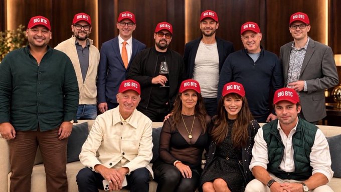A group of ten people pose together in suits and formal attire, each wearing a red "BIG BTC" cap, captured at a Bitcoin gathering in Manhattan that evening. The matching hats and the post's caption emphasize a unified, optimistic stance on Bitcoin ("BIG BTC").