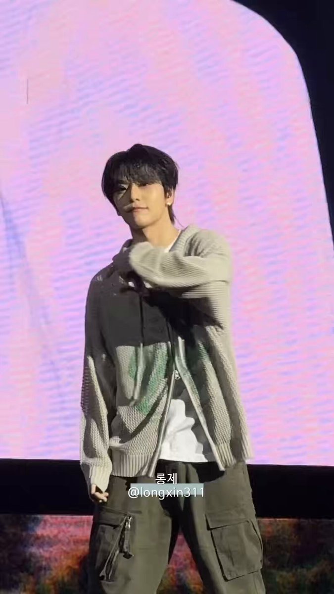 가장 적용하는 경우, a man wearing a grey sweater with green designs standing against a pink background.