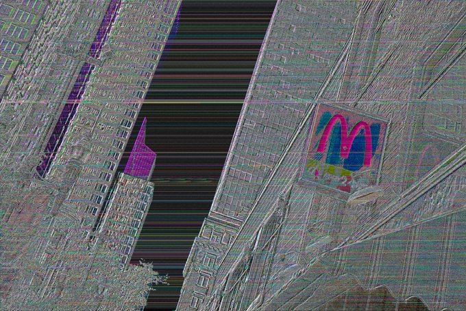 Heavily distorted/glitched image showing buildings with a McDonald's 'M' logo visible, rendered with heavy digital artifacts and horizontal line distortions.