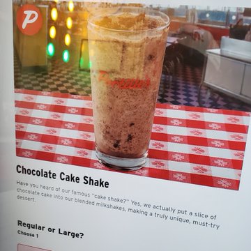 Mobile menu screen from Portillo's featuring a Chocolate Cake Shake, describing a milkshake blended with a slice of chocolate cake, with options for Regular or Large.