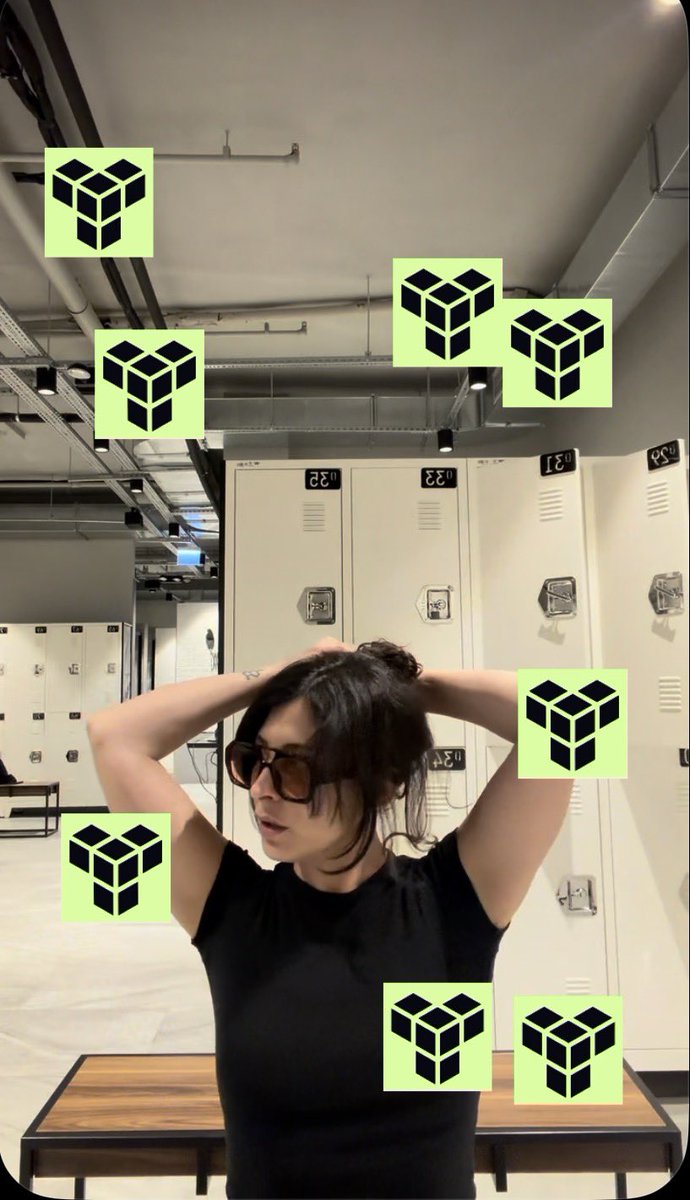 A woman wearing sunglasses and a black top is posing in what appears to be a locker room, with her hands behind her head, while several green logos resembling the Band Protocol logo are overlaid on the image.