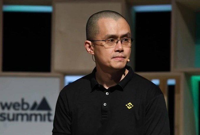 Changpeng Zhao (CZ), the former CEO of Binance, wearing a black polo shirt with the Binance logo while speaking at a Web Summit event.