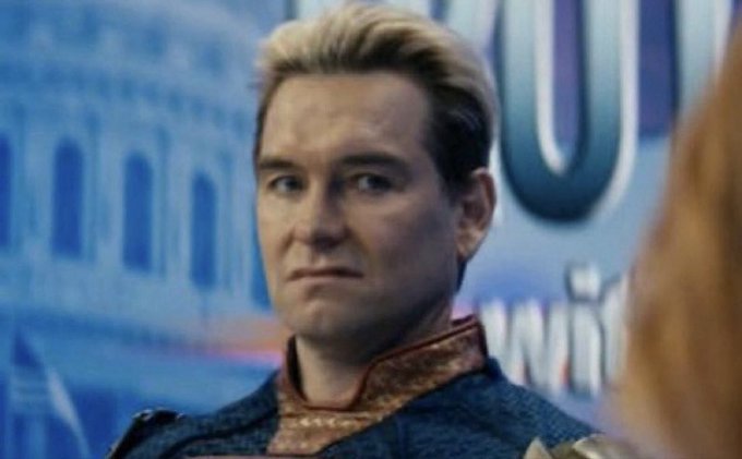 The image features a man with blonde hair wearing a blue shirt, looking at someone off-camera. The background shows an advertisement for a product called "Solana", which has a blue color scheme. This suggests that the photo might be related to a promotional campaign or advertisement featuring the character Solana from the TV show "The Walking Dead".