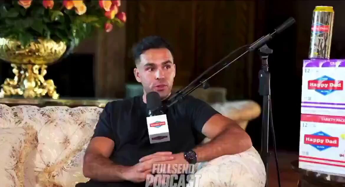 In the image, a man wearing black sits comfortably on a couch with his legs crossed. He holds a microphone, possibly recording or broadcasting an interview, with the focus on him. In the background, there's another person sitting on a chair near the couch, and a vase filled with flowers is placed nearby. 

The main image shows Bitcoin being discussed, as it says in the caption "Bitcoin is going to hit $1,000,000". The post also mentions Eric Trump talking about Bitcoin, which further supports its connection to the image.