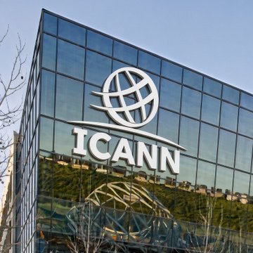 The image shows the ICANN (Internet Corporation for Assigned Names and Numbers) headquarters building with its distinctive logo and acronym prominently displayed on the glass facade. The caption connects the organization, which manages the global domain name system, to the news that ICANN has received a formal application for .BITCOIN domain registration, signaling cryptocurrency's growing mainstream integration.