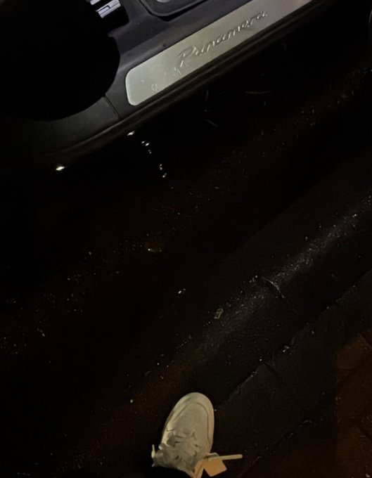 A sneaker dangles from a New York City fire escape above the street, with the illuminated sill of a Range Rover visible in the background, captioned "Gn bros."