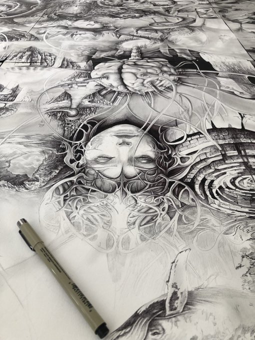 An intricate black and white pen drawing featuring a surreal face surrounded by flowing organic patterns, with a Micron pen resting on the artwork for scale.
